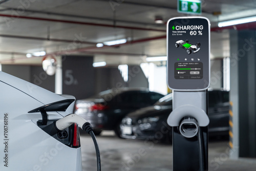 Fototapeta Naklejka Na Ścianę i Meble -  EV electric car recharge at shopping center parking lot charging in downtown city showing urban sustainability lifestyle by green clean rechargeable energy of electric vehicle innards