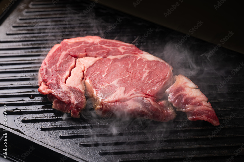 fresh ribeye steak on hot grill with smoke