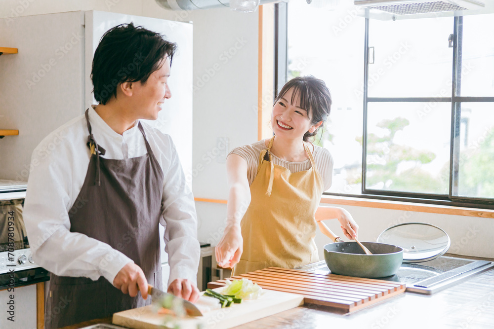 キッチンで料理をする夫婦・包丁で野菜を切る男性
