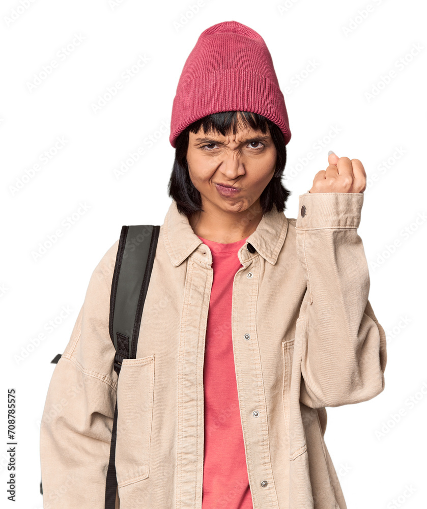 Young student with backpack and beanie in studio showing a copy space on a palm and holding another hand on waist. Young student with backpack and beanie in studio showing a copy space on a palm and holding another hand on waist.