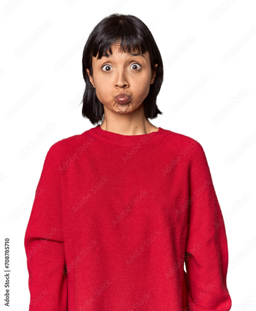 Young Hispanic woman with short black hair in studio blows cheeks, has tired expression. Facial expression concept. Young Hispanic woman with short black hair in studio blows cheeks, has tired expression. Facial expression concept.