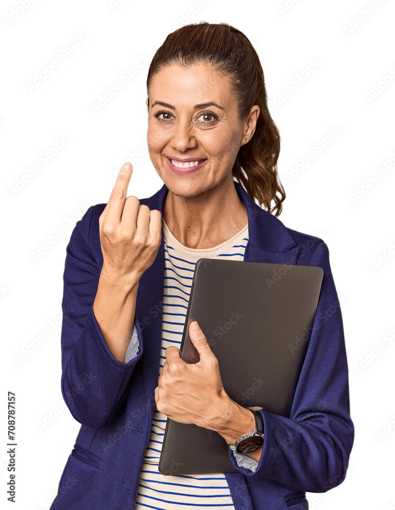 Middle-aged entrepreneur with laptop in studio pointing with finger at you as if inviting come closer.