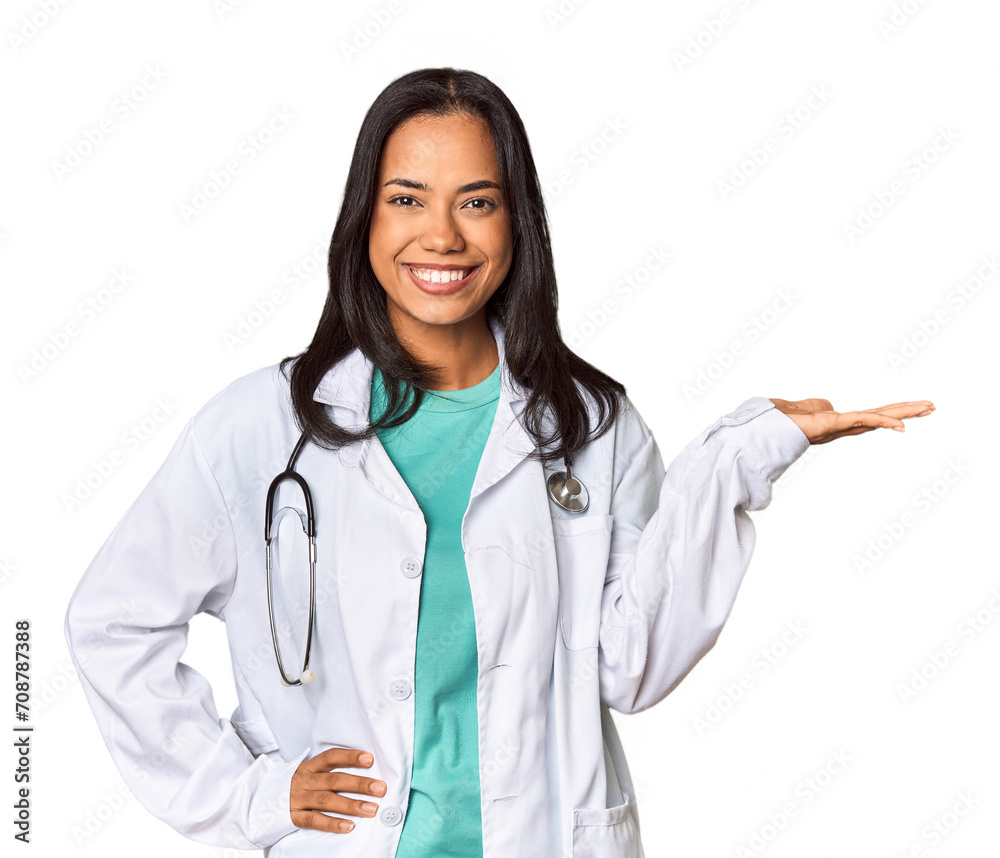 Young Filipina doctor with stethoscope in studio showing a copy space on a palm and holding another hand on waist. Young Filipina doctor with stethoscope in studio showing a copy space on a palm and holding another hand on waist.
