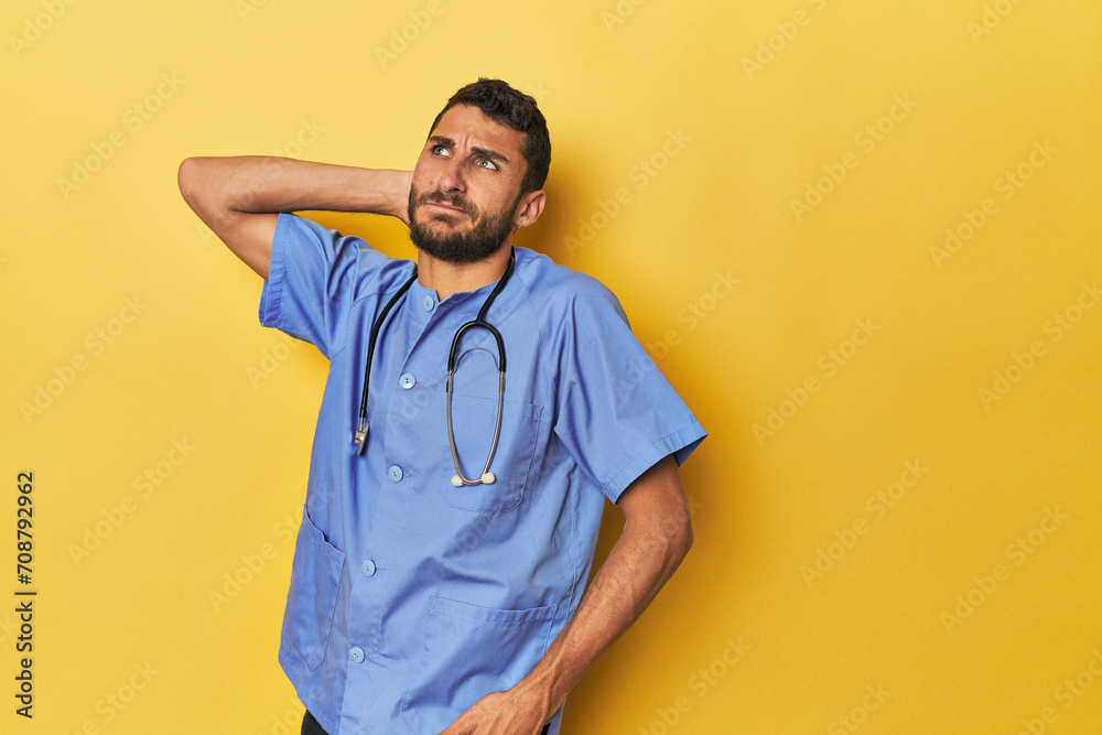 Young Hispanic male nurse Young Hispanic male nurse poses confidently touching back of head, thinking and making a choice.< mixto > Young Hispanic male nurse Young Hispanic male nurse poses confidently touching back of head, thinking and making a choice.< mixto >