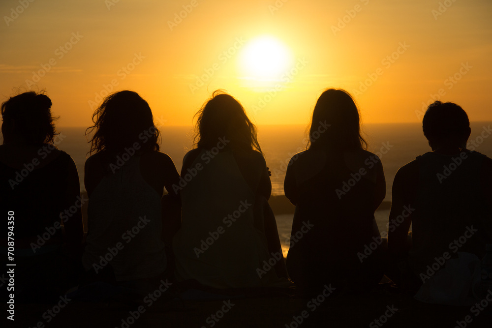 Silhouette of people watching a sunset from the top of a mountain 