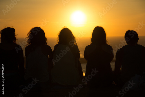 Silhouette of people watching a sunset from the top of a mountain 