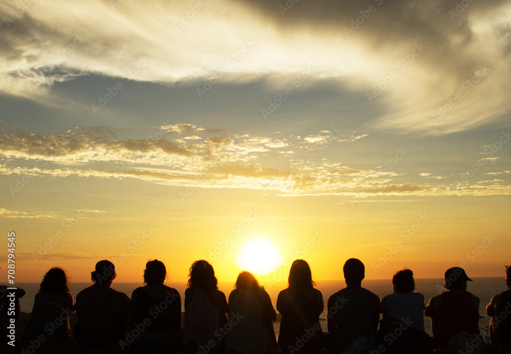 Silhouette of people watching a sunset from the top of a mountain 