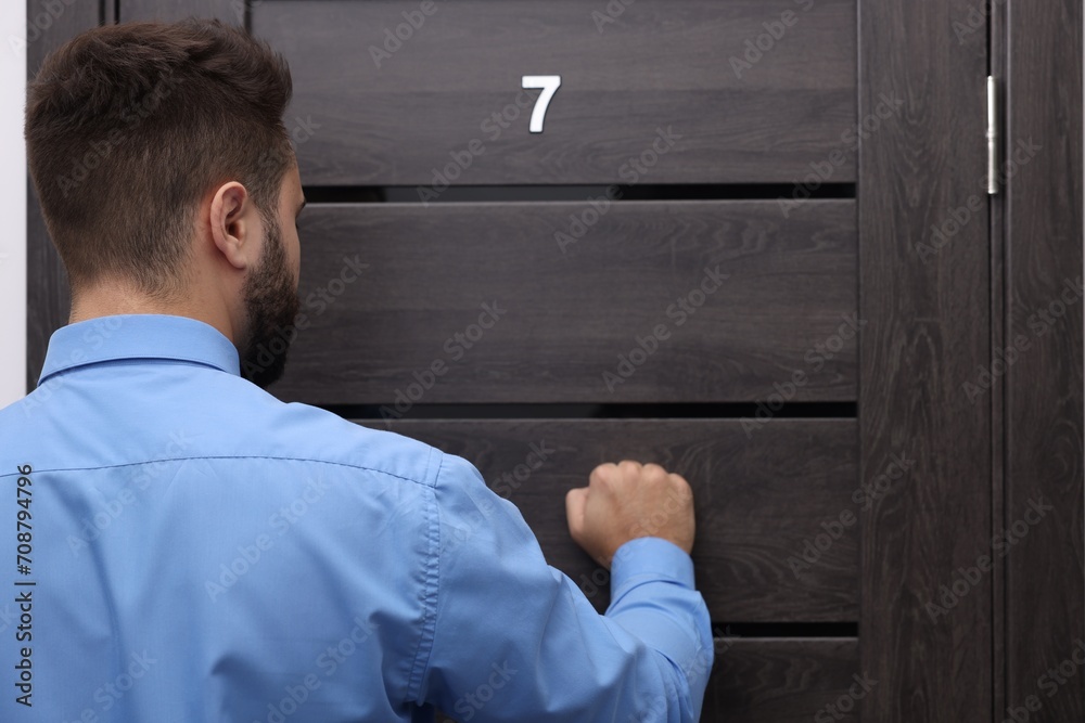 Collection agent knocking on wooden door, back view Collection agent knocking on wooden door, back view