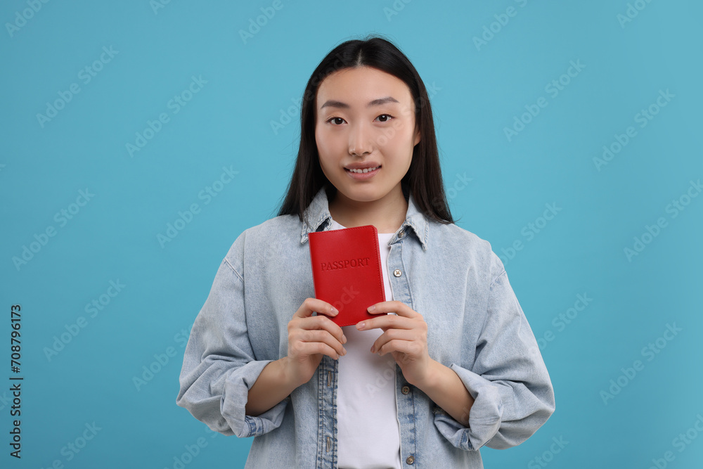 Immigration. Happy woman with passport on light blue background Immigration. Happy woman with passport on light blue background