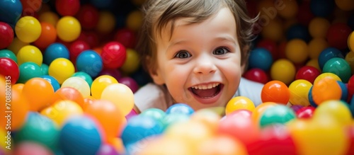 Child in ball pit at play room or indoor playground for kids, like day care or preschool.