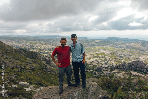 father and son pose in the top of a mountain with a really nice view