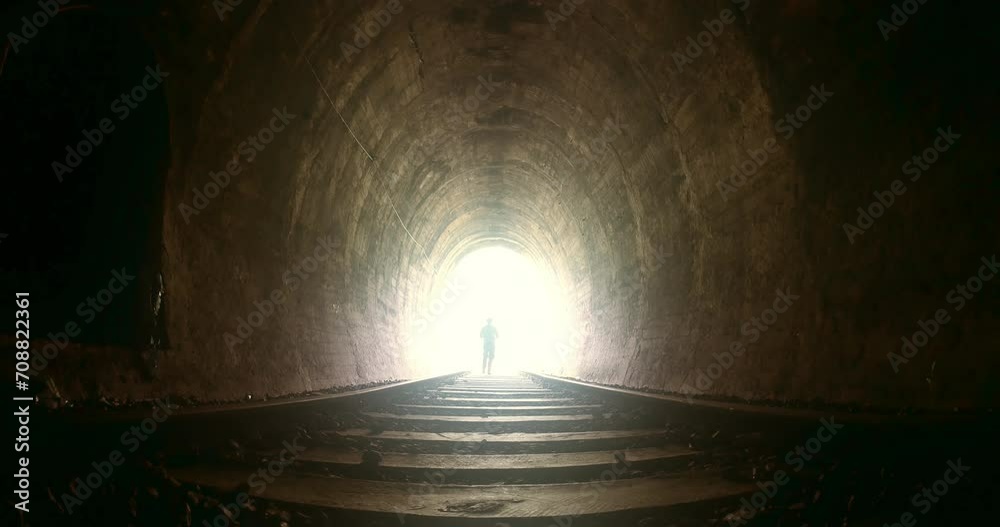 Man running into bright light in the end of dark tunnel