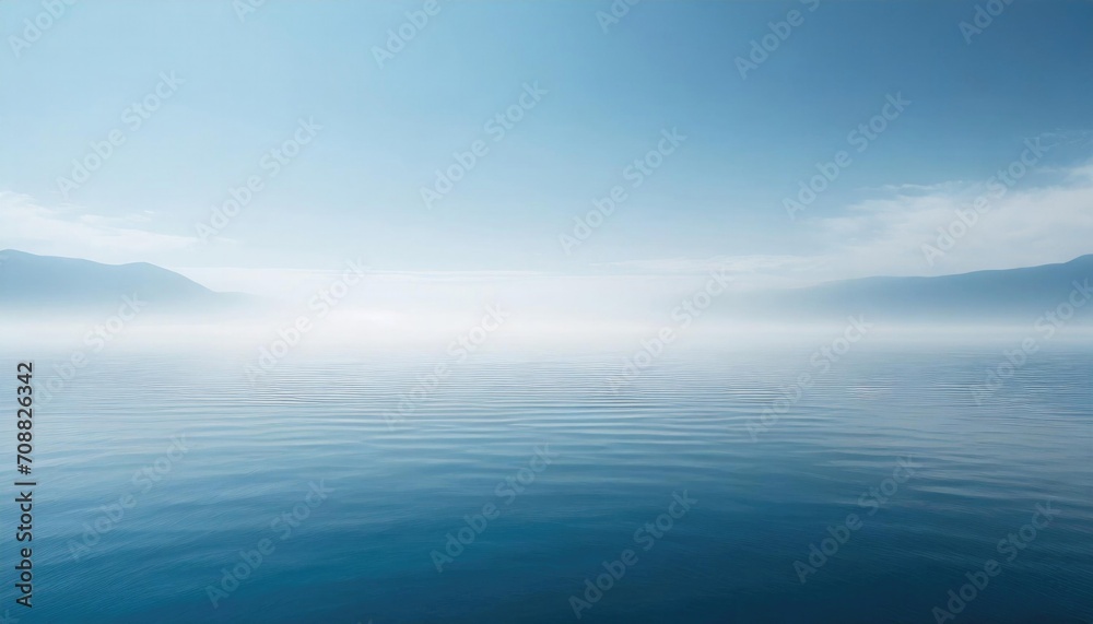 Serene seascape with a tranquil blue sea merging with a foggy sky and distant mountains.