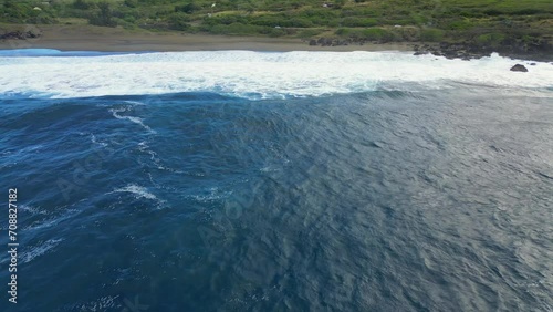 Play of waves on a black sand beach at Reunion Island