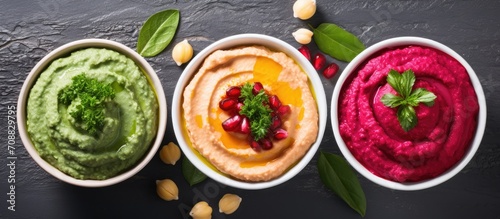 Top view of bowls with hummus made from chickpeas, spinach, and beets, arranged flat.