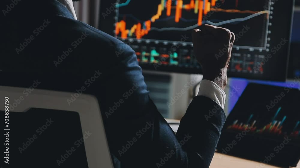 Financial Analyst Working on a Computer with Multi-Monitor Workstation with Real-Time Stocks, Commodities and Foreign Exchange Charts. Businessman Works in Investment Bank City Office at Night. Financial Analyst Working on a Computer with Multi-Monitor Workstation with Real-Time Stocks, Commodities and Foreign Exchange Charts. Businessman Works in Investment Bank City Office at Night.