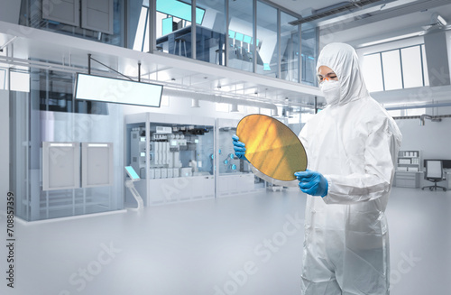 Engineer wears protective suit with silicon wafer for semiconductor manufacturing photo