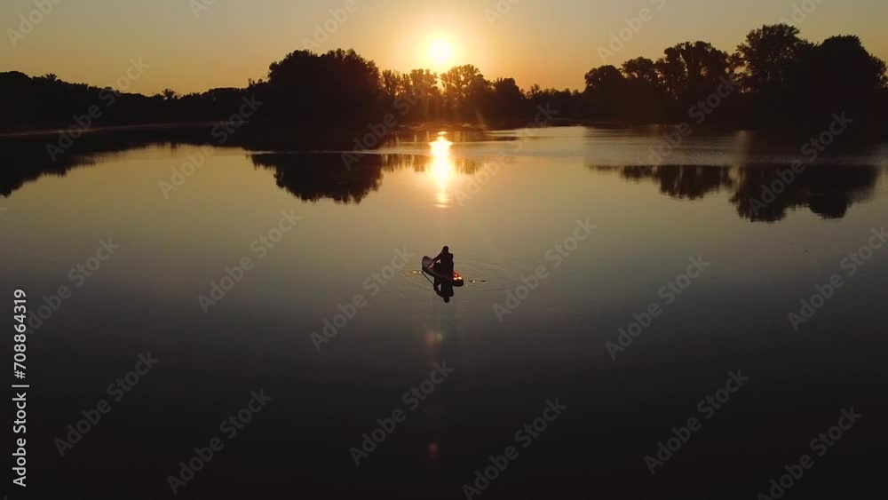 a man swims on a lake on a sap board at dawn