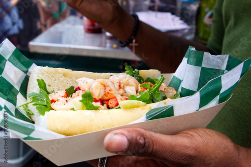 A delicious shrimp sandwich purchased at a food truck festival is just seconds from being devoured. photo