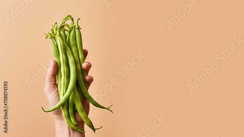 Hand holding green bean vegetable isolated on pastel background