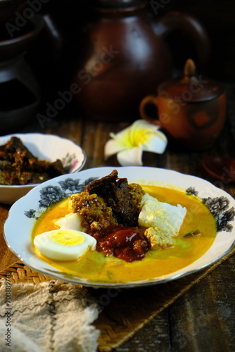 A bowl of Lontong Ketupat or Lontong Kupat or Rice Cake and coconut gravy with tumeric, chilli, and vegetables. A famous Malaysian and Indonesia food.