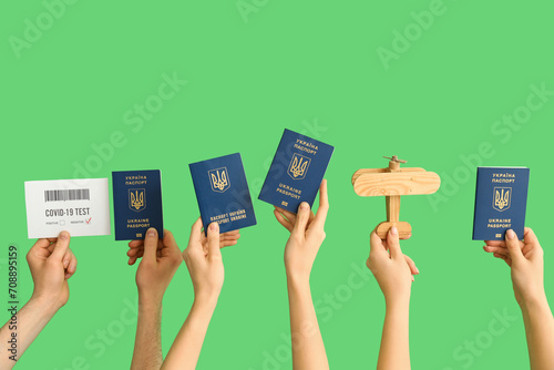 Women with Ukrainian passports, wooden airplane and negative covid-19 test result on green background photo