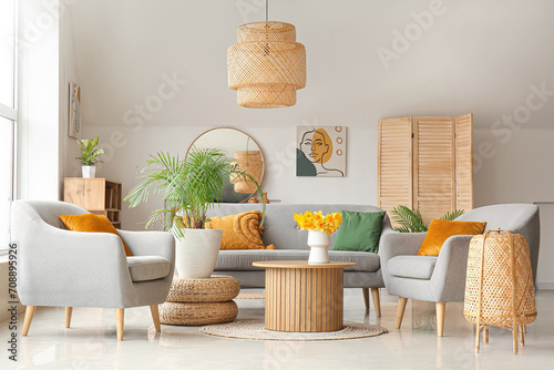 Interior of cozy living room with sofa, armchairs and flower vase on coffee table