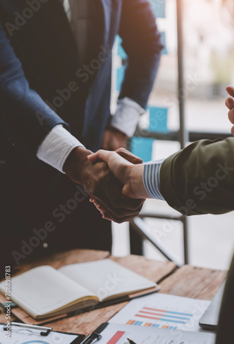Two confident businessmen holding hands during a meeting in the office, success, management, colleagues standing and applauding, wishing congratulations. Alliance concept.