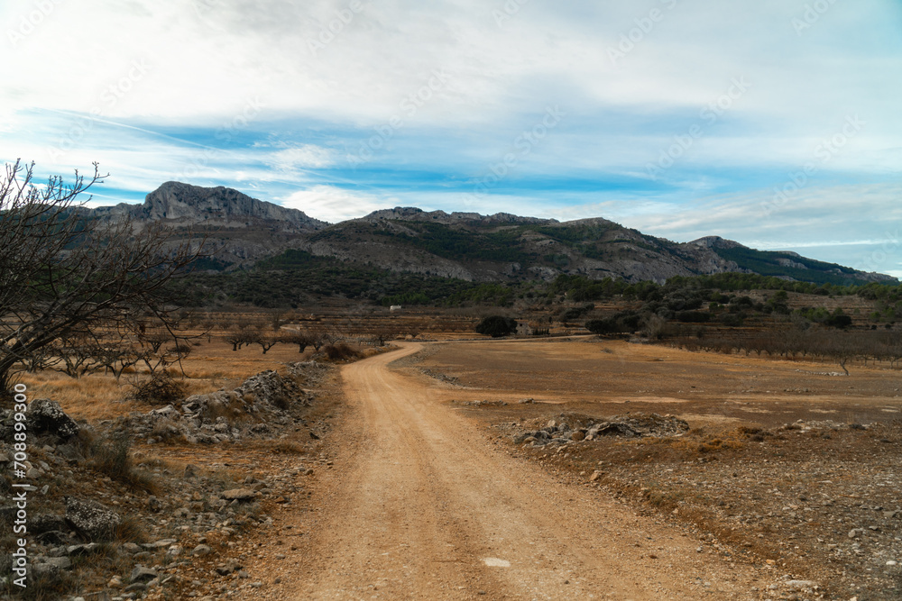Landscape with a dirt road and mountains on background