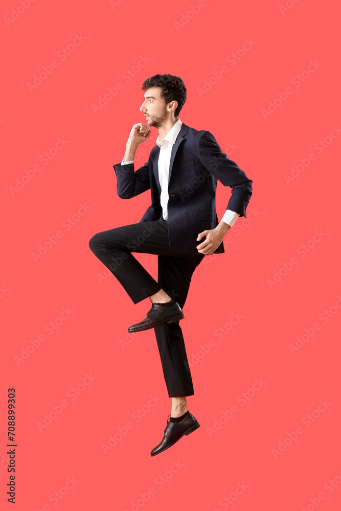 Young man in suit jumping on red background Young man in suit jumping on red background
