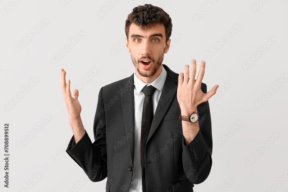 Surprised young businessman in suit on light background Surprised young businessman in suit on light background