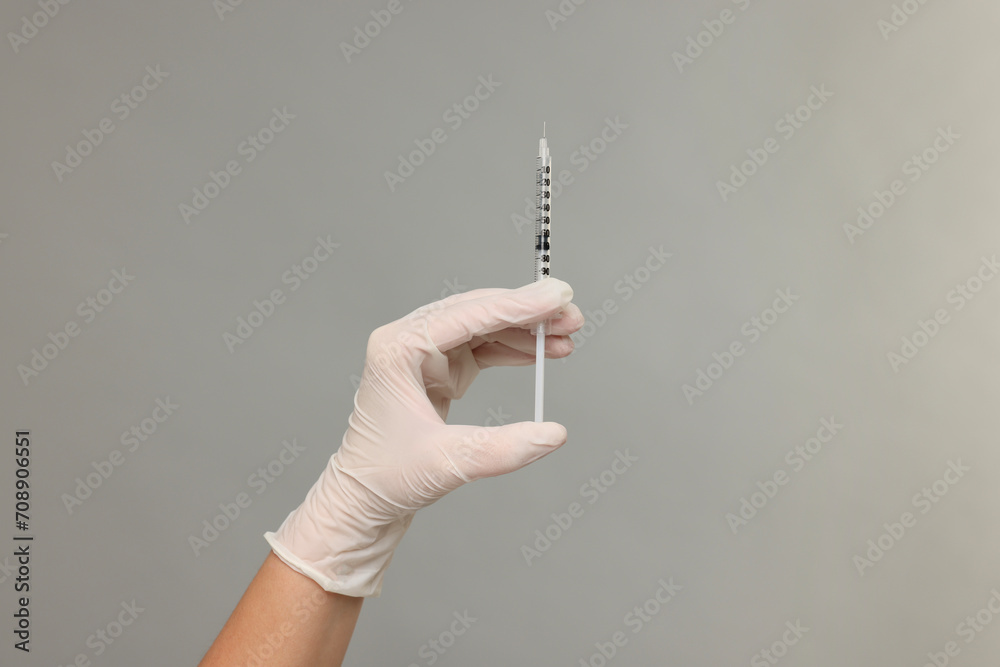 Doctor holding medical syringe on grey background, closeup Doctor holding medical syringe on grey background, closeup