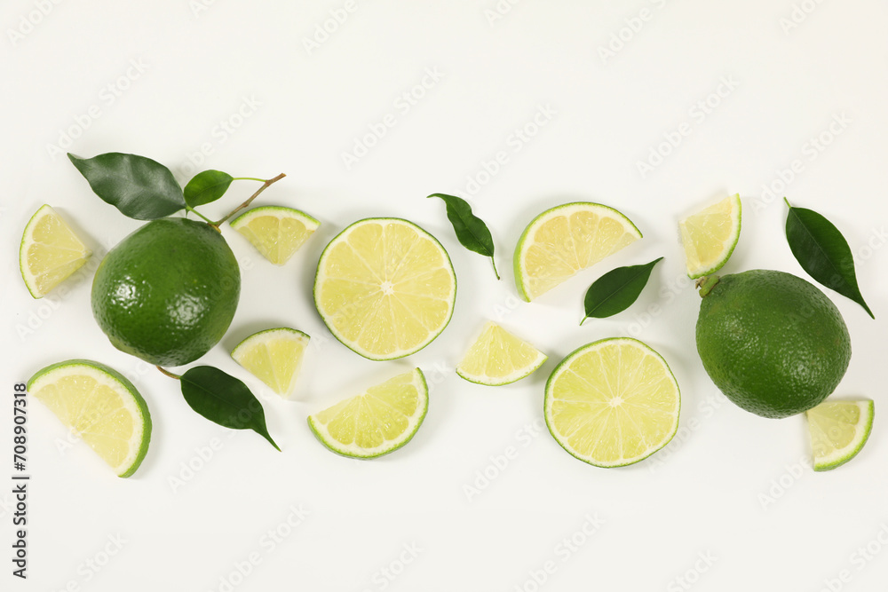 Limes, ice and green leaves on white background, flat lay
