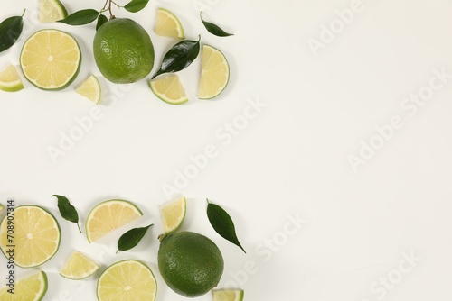 Limes, ice and green leaves on white background, flat lay. Space for text
