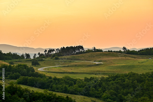 Beautiful sunset panorama serpentine road in Transylvania  with grasses  trees and mountains in the background  Hunedoara  Romania