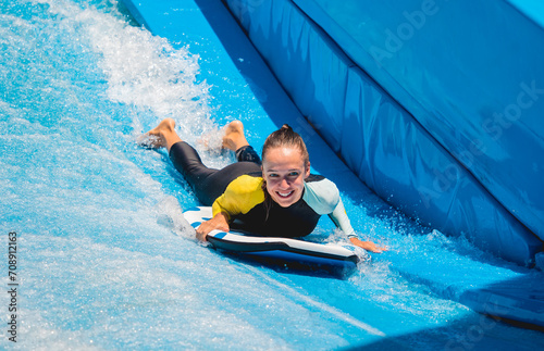 Beautiful young woman surfing on a wave simulator at a water amusement park © romaset