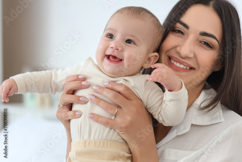 Happy mother with her little baby in bedroom, closeup