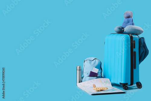 Suitcase with travelling accessories on blue background © Pixel-Shot