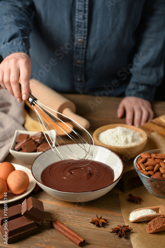 Woman preparing tasty melted chocolate at table