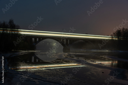 Night Train Crossing Illuminated Bridge over Water at Dusk