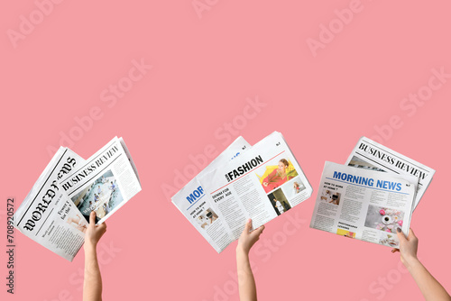 Women with newspapers on pink background