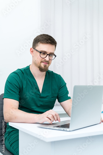 Hospital specialist working with laptop. Smart handsome medical specialist portrait.