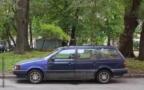 An old dark blue car is parked near the lawn, Tallinskaya Street, Saint Petersburg, Russia, September 26, 2023