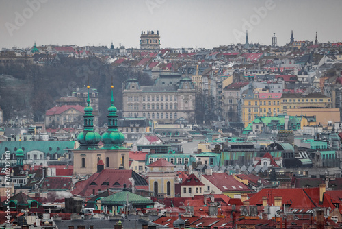 A cityscape view of the old historic medieval city of Prague with many rooftops. There is a church and a tower. It was freezing cold in winter