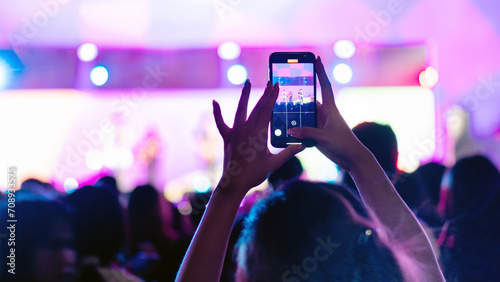 Girl holding smart phone and recording and photographing in music festival concert, event background concept 