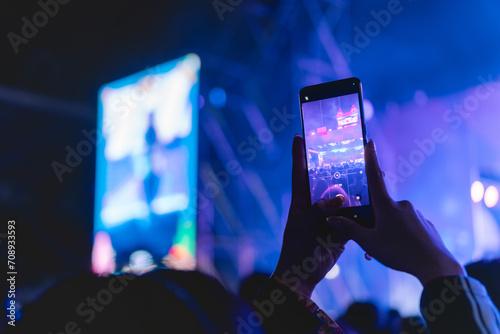 Girl holding smart phone and photographing in music festival concert, party event background concept 