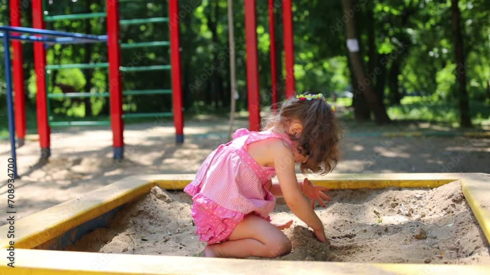 Little girl in a pink dress is digging hole on sandbox. Little girl in a pink dress is digging hole on sandbox.