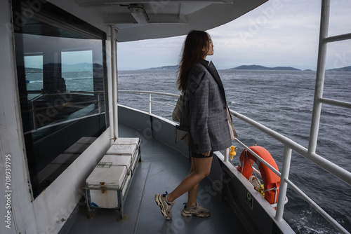 Istanbul. An Asian girl in a man's jacket is sailing on a ferry in Istanbul in cloudy weather, standing on the upper deck with a lifebuoy in the background photo
