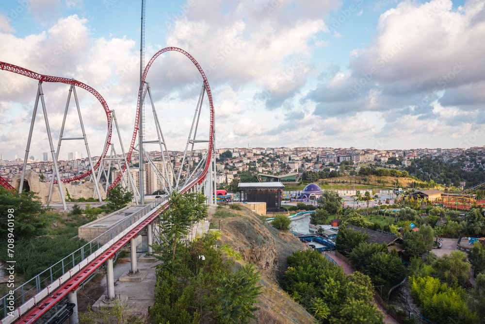 Roller coaster in an amusement park located on a hill on a sunny cloudy day