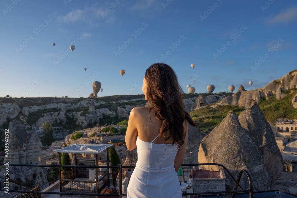 Cappadocia, Asian woman watches the flight of hot air balloons early in the morning in Cappadocia, tourism in Turkey